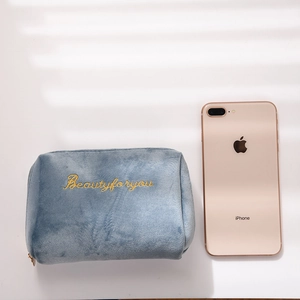 Detailed embroidery of gold text on blue velvet cosmetic bag with zipper and soft texture