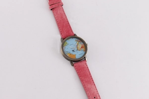 Close-up of pink denim strap watch with world map dial and airplane shaped hand