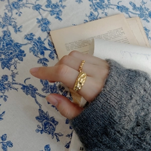 Detail of a textured irregular gold ring worn on hand with a vintage book background