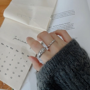 Close-up of irregular textured 925 sterling silver rings worn on model fingers