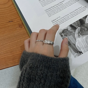 Close-up of wavy and organic 925 silver rings on hand with aesthetic book background
