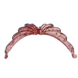 Macro detail of amber resin banana hair clip featuring intricate wing texture and combs