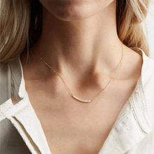Dettaglio di una collana d'oro a onda con perle d'acqua dolce naturali indossata da modella