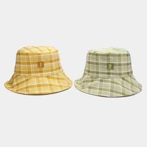 Dettaglio di cappelli alla pescatora a quadri gialli e verdi con patch simboliche