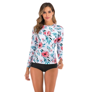 Detail of floral long sleeve bikini top with half-zipper and black swimming shorts