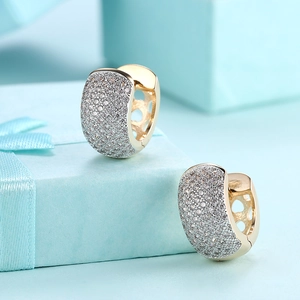 Macro shot of gold U-shaped hoop earrings with micro-paved white zircons on blue box