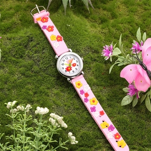 Close-up of pink children's cartoon watch with 3D embossed flowers on a grass background