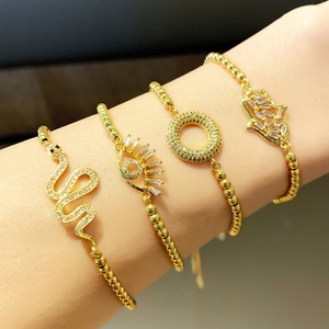 Detail shot of four gold beaded bracelets with snake and hamsa charms on a woman's wrist