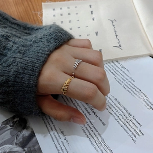 Detail of adjustable laurel leaf rings in gold and silver finish on a female hand