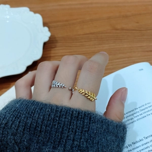 Close-up of elegant gold and silver leaf-shaped open rings with crystals on hand