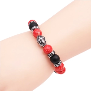 Dettaglio di bracciale con perle rosse, sfere nere opache e ciondolo a testa di Buddha