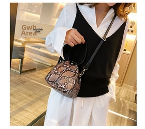 Fashionable snake print mini bucket bag worn with a casual vest and shirt outfit