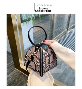 Detail of snake pattern brown pyramid bag with black round handle and gold hardware