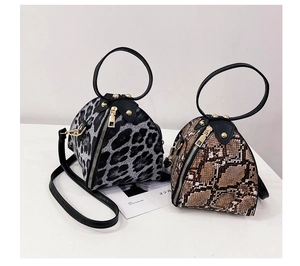 Detail view of leopard and snake print pyramid handbags with round handles and gold hardware