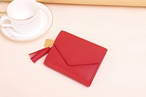 Detail of red faux leather wallet featuring a stylish tassel and golden heart charm pendant