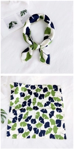 Detail of silk square scarf showing green ginkgo leaf print and premium edge stitching