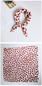 Detail view of square silk scarf with red heart patterns and smooth glossy finish