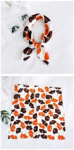 Detail of silk square scarf with orange ginkgo leaf print and fine stitched edges