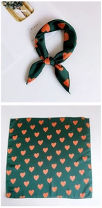 Detail of silk square scarf showing dark green satin with orange heart print pattern