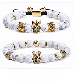 Macro detail of 8mm white turquoise beads with a golden crown charm and zircon inlay