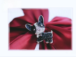 Macro shot of French Bulldog brooch with black and white rhinestones on red silk
