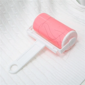Washable pink lint roller for clothes with a plastic handle on white knitted fabric