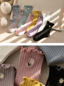 Close-up of premium cotton socks featuring ruffle edges and delicate daisy embroidery