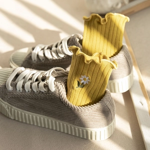 Yellow ruffle trim socks with daisy embroidery and ribbed knit texture shown with casual shoes