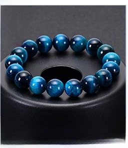 Macro detail of natural blue tiger eye beaded bracelet with cat eye effect on black stand