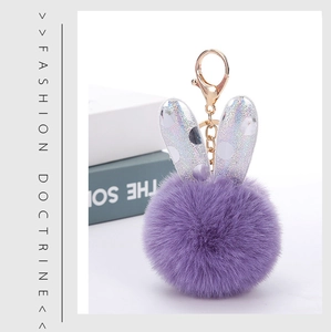 Detail of purple faux fur pompom keychain with silver sequin rabbit ears and gold clasp