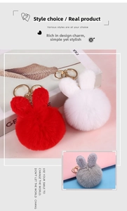 Close-up of plush rabbit ear pompom keychains in red, white and grey with gold metal clips