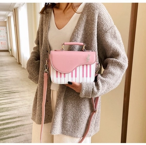 Close-up of pink piano keyboard print and gold music note hardware on a stylish PU handbag