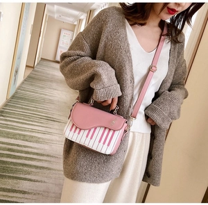 Detail of piano key print handbag with gold treble clef clasp and adjustable pink strap