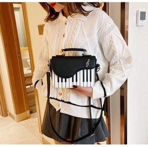 Fashion piano keyboard pattern crossbody bag with silver music note icon on a white knit top