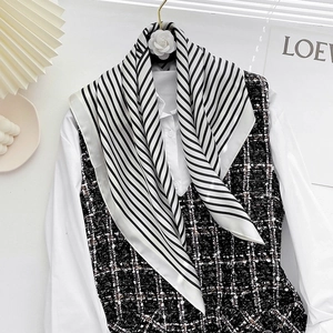 Detail of a black and white striped silk scarf styled with a tweed vest for a French look