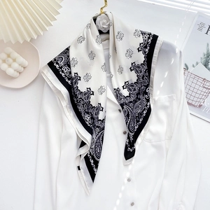 Detail of black and white paisley silk scarf draped on a white shirt as stylish necktie