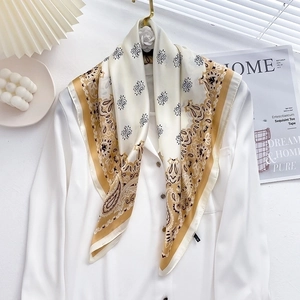 Detailed paisley silk scarf in gold and ivory draped over a white dress shirt