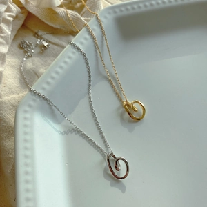 Dettaglio di collane a spirale in argento e oro su un piatto di ceramica