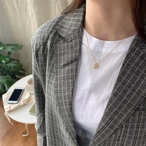 Primo piano di una collana minimalista con anelli d'oro intrecciati su una modella