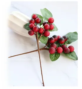 Detail of red artificial berry stems in ceramic vase with frosted texture and green leaves