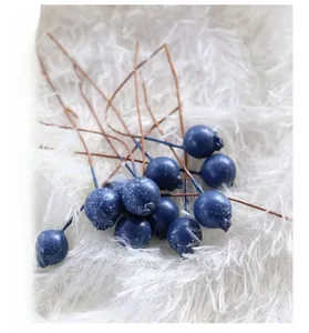 Detailed close-up of dark blue artificial berries with white frost on brown stems