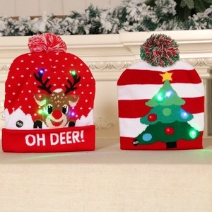 LED knitted Christmas beanies with reindeer and tree patterns on a festive mantle