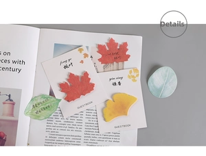 Dettaglio di foglietti adesivi a forma di foglia di acero e ginkgo su pagine di libri