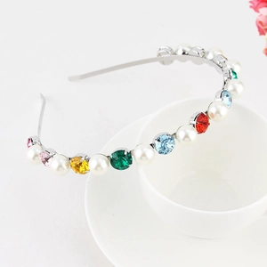 Detail of a thin silver headband with colorful rhinestones and pearls on a coffee cup