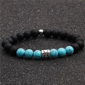 Detail of matte black and turquoise beads with silver Pisces zodiac charm on the bracelet