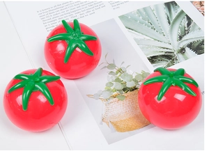 Three realistic tomato squeeze stress relief toys placed on an open magazine page