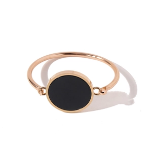 Detailed view of rose gold bracelet featuring a round black medallion and minimalist design