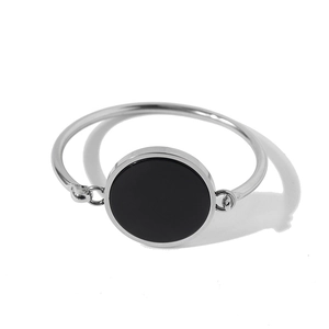 Close-up of a silver metal bangle featuring a polished round black stone inlay