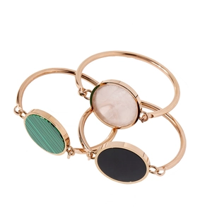 Three gold bangles with green malachite, pink crystal, and black onyx circular inlays