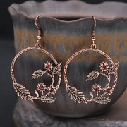 Détail de boucles d'oreilles rondes en bronze vintage avec motifs floraux et strass rouges